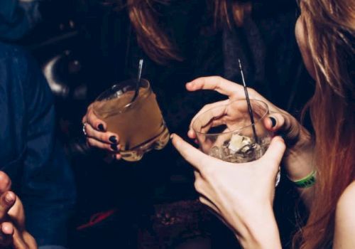 People holding drinks and laughing together, possibly at a social gathering or party.